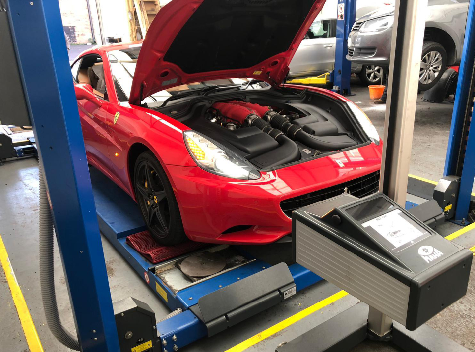 A red vehicle on a ramp with its bonnet open - MOT & Servicing Bletchley